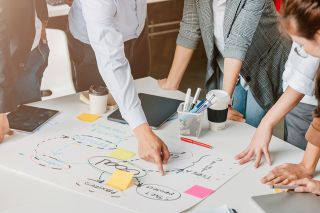 Foto: Personen diskutieren eine Flipchart